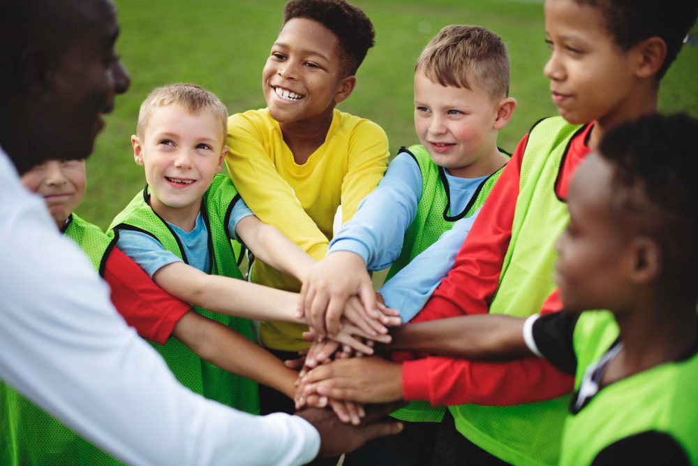 L'équipe de football junior s'empile les mains avant un match